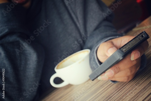 Woman using smart phone with coffee cup