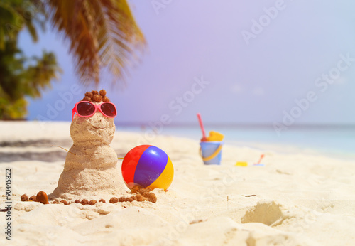 Sandy snowman and toys at sand beach