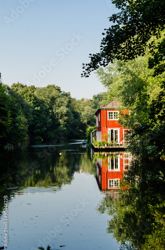 Rotes Holzhaus spiegelt sich im See