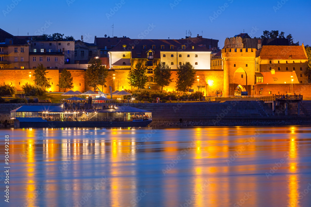 Old town of Torun at night reflected in Vistula river, Poland