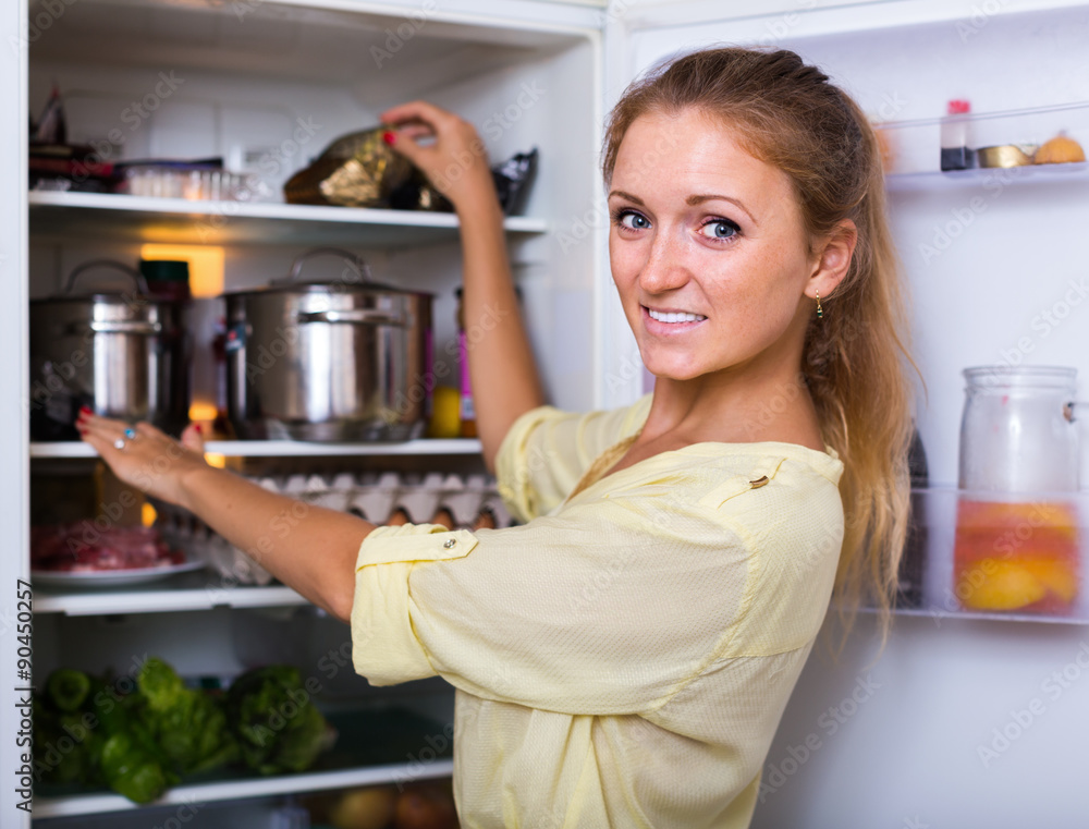 Housewife arranging food on fridge shelves