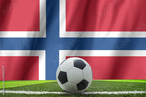 Soccer ball and national flag of Norway lies on the green grass
