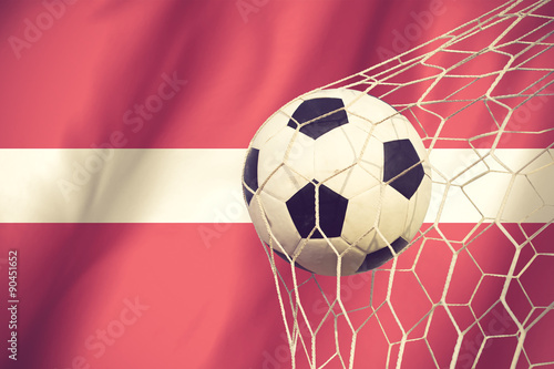 Latvia flag and soccer ball  football in goal net vintage color