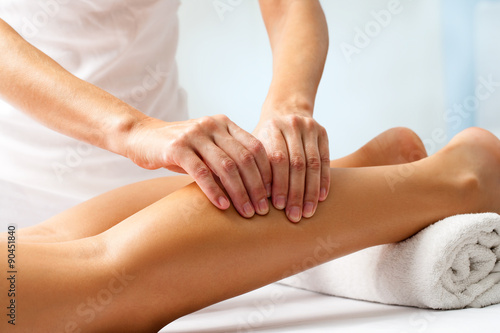 Detail of hands massaging human calf muscle.