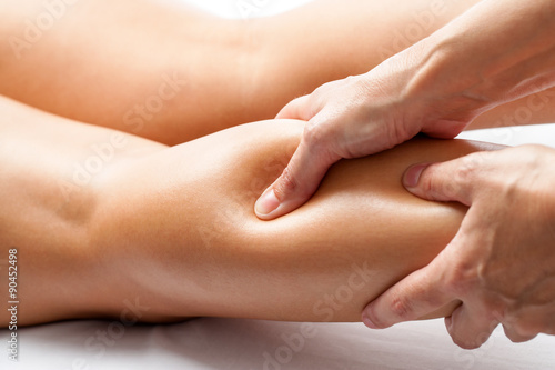 Foto Therapist applying pressure with thumb on female calf muscle.