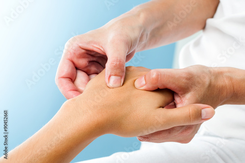Therapist doing massage on female hand.