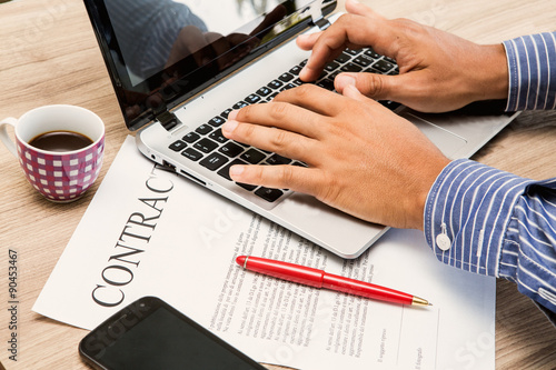 mani sulla tastiera di un notebook con contratto di assunzione di lavoro