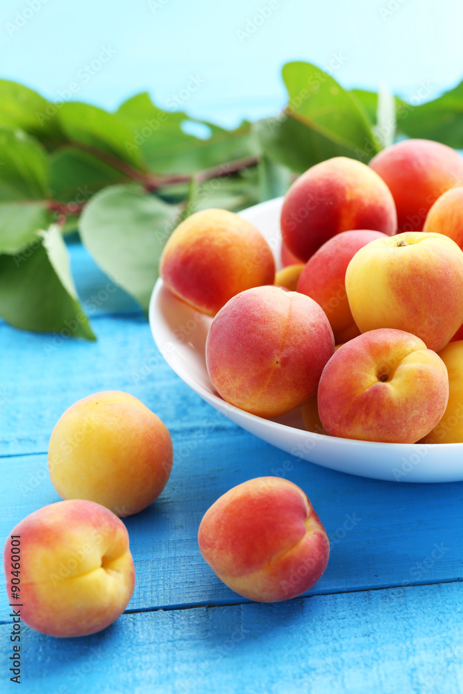 Fresh apricots in plate on a blue wooden background