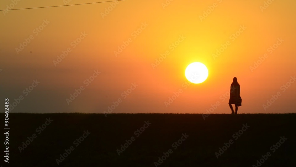 eine Person geht von recht s nach links als Silhouette durch die tief stehende Sonne eine Person geht von recht s nach links als Silhouette durch die tief stehende Sonne