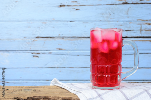 Red soda in glass put on wood background.
