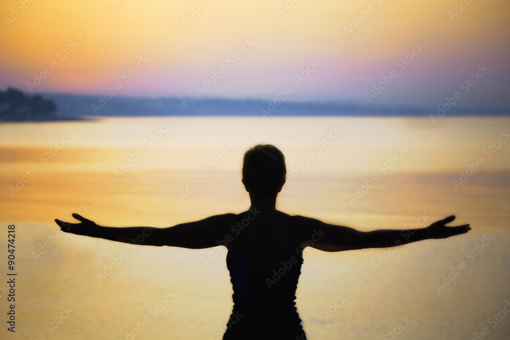 silhouette of woman taking a deep breath at the sunset