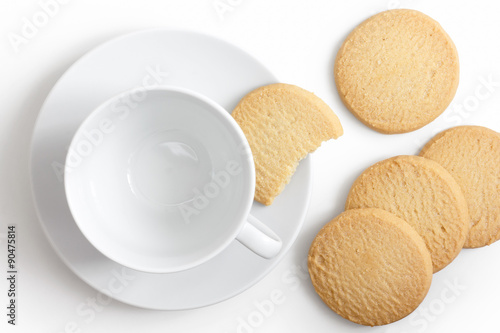 Empty white cup and saucer with shortbread biscuits from above.