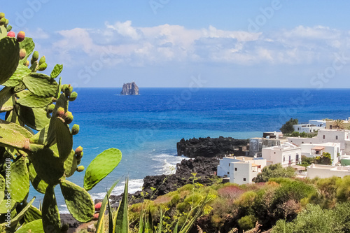 Coastline of Stromboli with prickly pear and white houses; Strombolicchio stack in the background photo