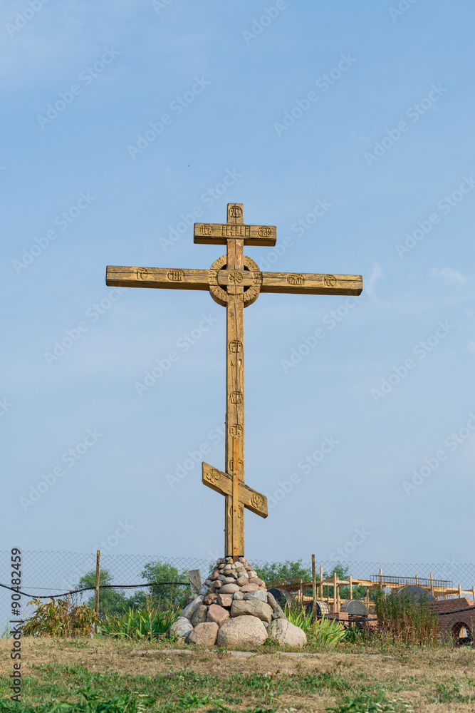 A wooden cross stands high against the blue sky
