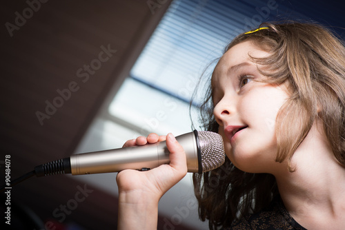 Little cute girl singing karaoke on microphone at home