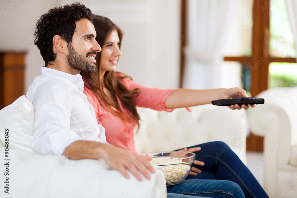 Fototapeta premium Young couple watching tv and eating pop-corn