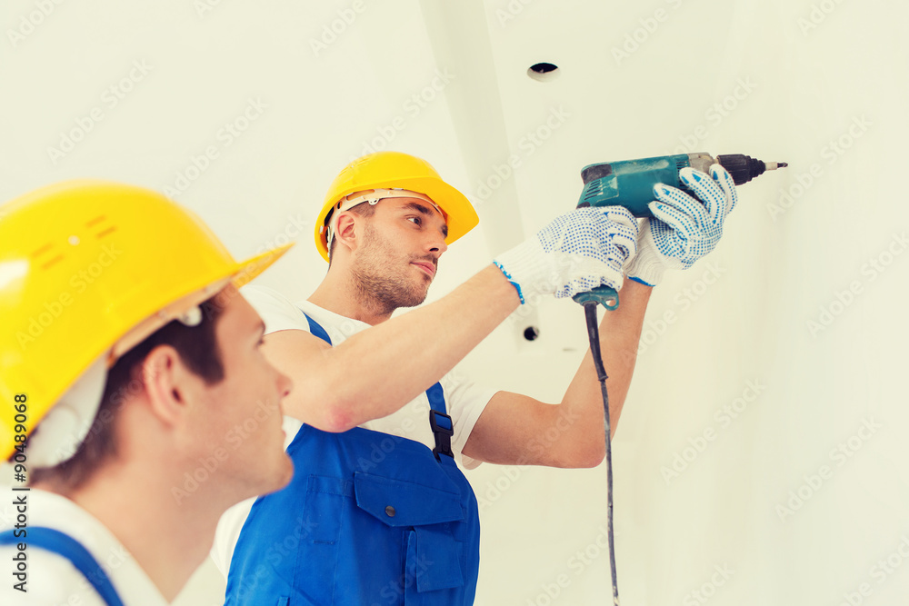 group of builders with drill indoors group of builders with drill indoors