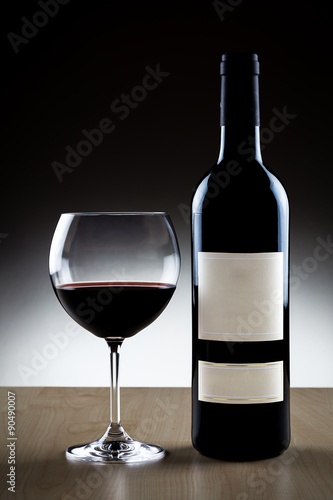 Bottiglia di vino rosso con bicchiere su sfondo nero