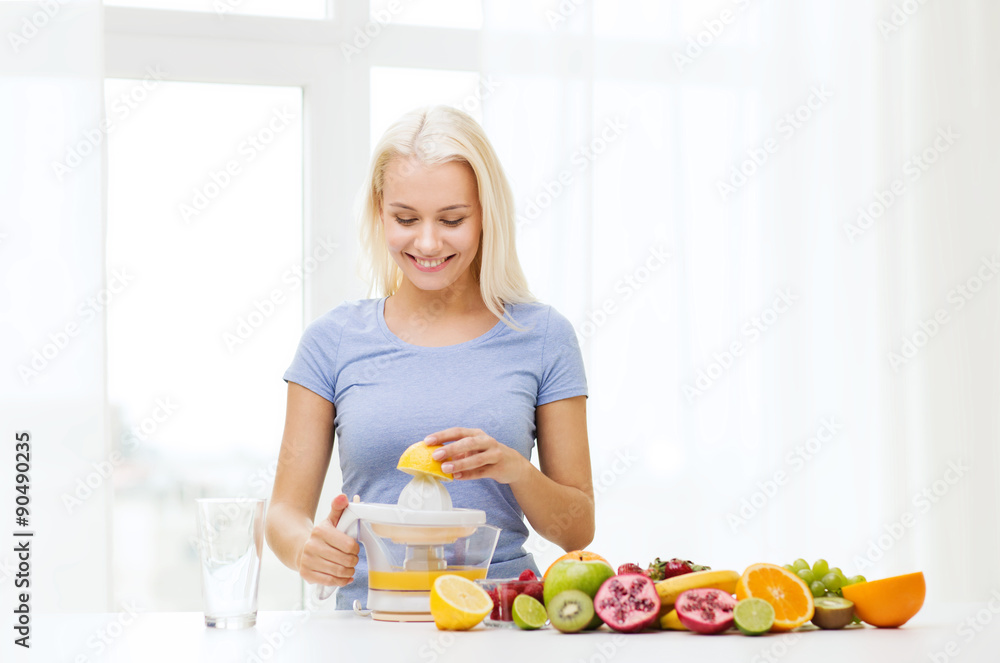 smiling woman squeezing fruit juice at home