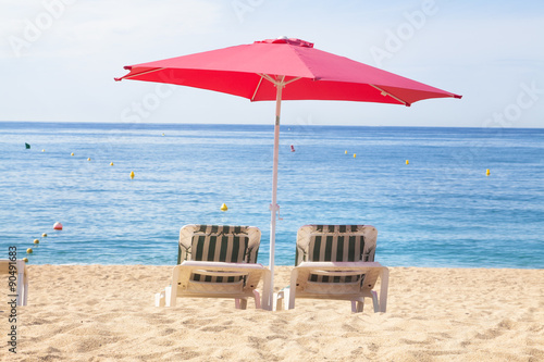 Fototapeta Naklejka Na Ścianę i Meble -  Two sun beds under umbrella on a tropical beach with a beautiful ocean view