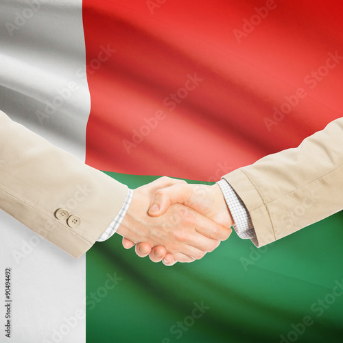 Businessmen handshake with flag on background - Madagascar
