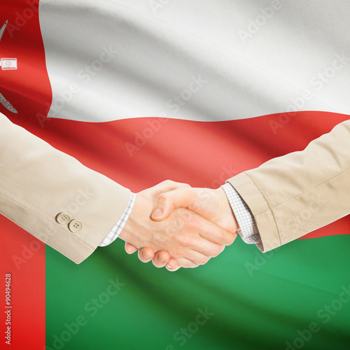 Businessmen handshake with flag on background - Oman
