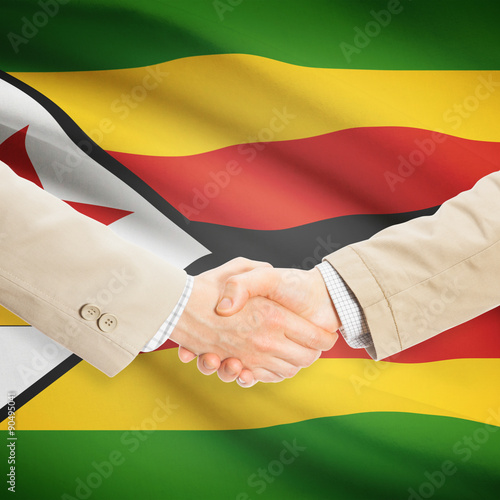 Businessmen handshake with flag on background - Zimbabwe