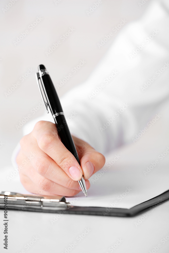 Female hand with pen writing on paper at workplace Female hand with pen writing on paper at workplace