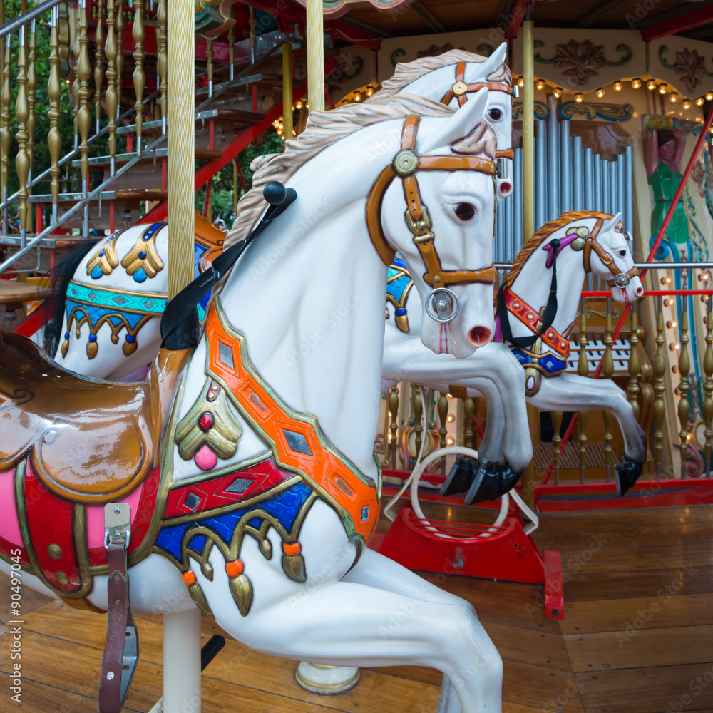 Old French carousel in a holiday park. Three horses and airplane on a traditional fairground vintage carousel. Merry-go-round with horses.
