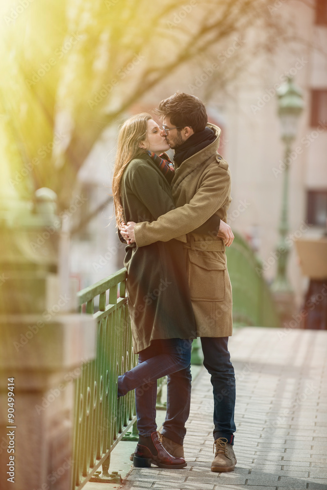 stylish young couple kissing on a bridge in the city