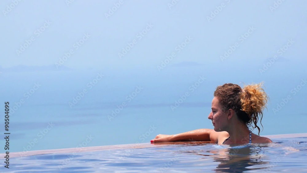 Young Woman Relaxing in Infinity Swimming Pool in Resort Young Woman Relaxing in Infinity Swimming Pool in Resort
