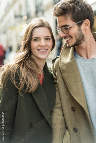 a young stylish couple walking in the street,looking at camera