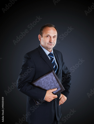 Confident businessman isolated on a dark background.