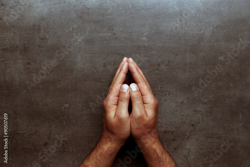 Pray, man hands on grey table background