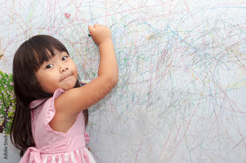 girl drawing with crayons on the wallpaper