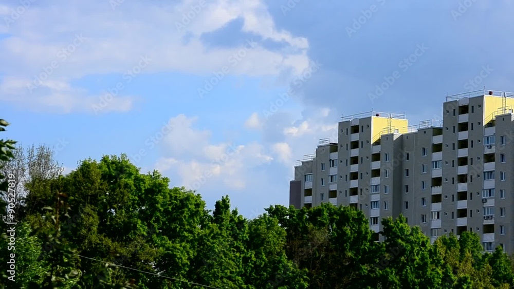 White and grey cumulus clouds move behind modern apartment block White and grey cumulus clouds move behind modern apartment block