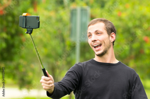 Hispanic man posing with selfie stick in park environment photo