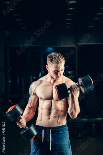 Athlete muscular bodybuilder training back with dumbbell in the
