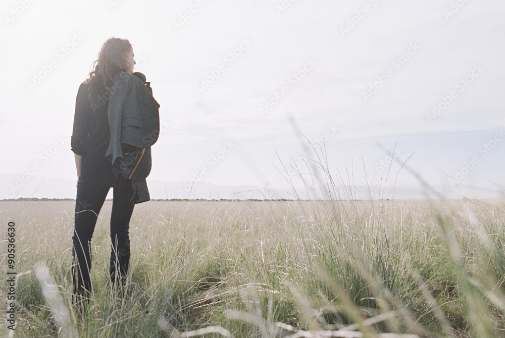 Woman standing looking to the horizon, carrying a jacket and backpack. Woman standing looking to the horizon, carrying a jacket and backpack.
