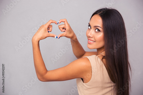 Obraz na plátně Woman making heart gesture with fingers