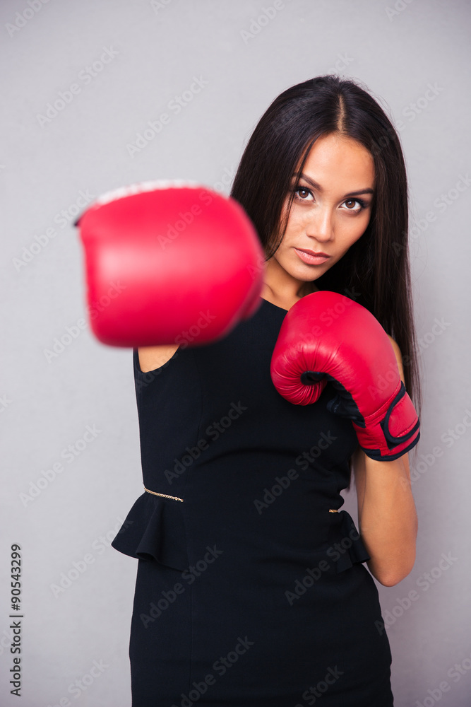Businesswoman in boxing gloves punching at camera Businesswoman in boxing gloves punching at camera