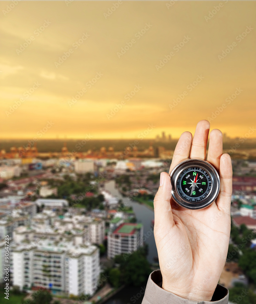 Business direction, Hand holding a magnetic compass over a city buildings