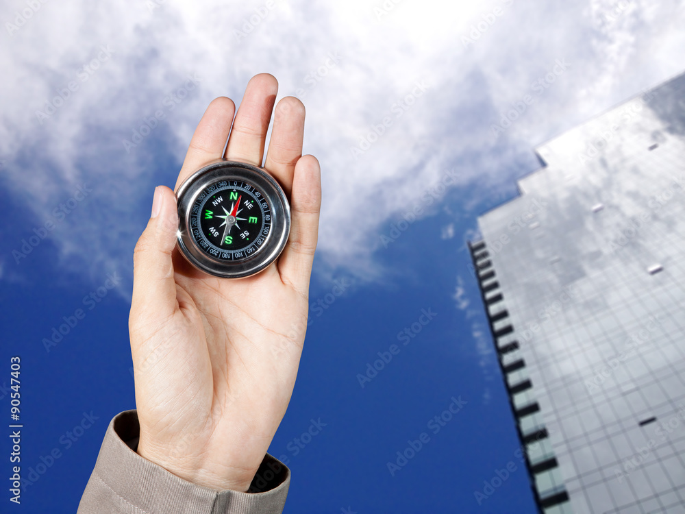 Business direction, Hand holding a magnetic compass over a city buildings