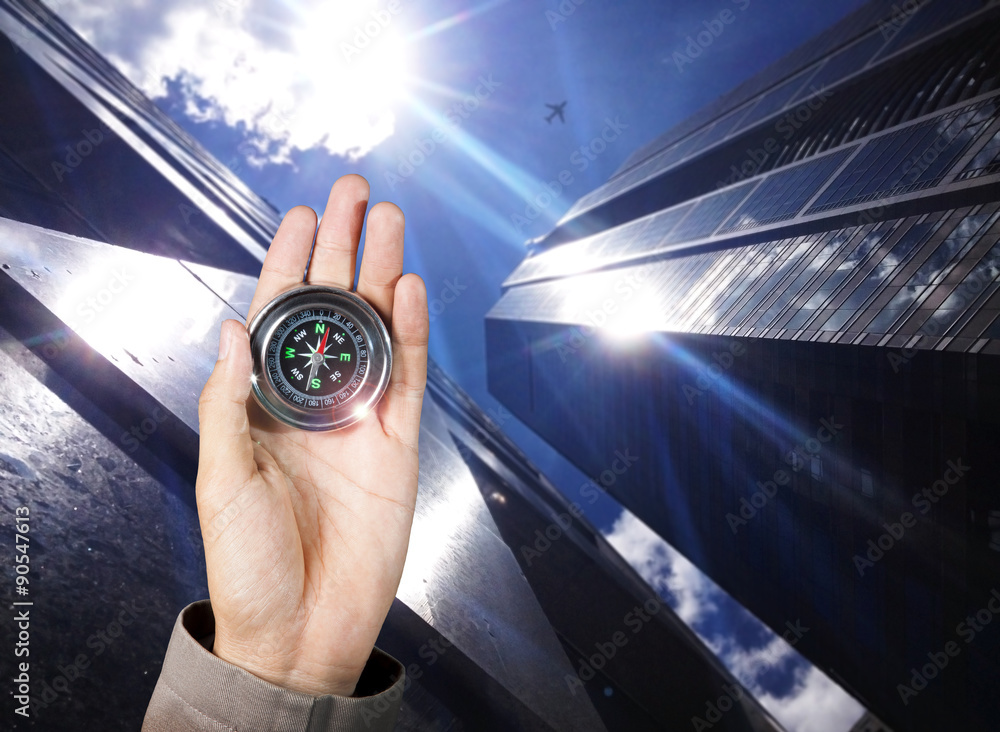 Business direction, Hand holding a magnetic compass over a city buildings