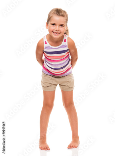 cute little girl standing on white holding hands behind back
