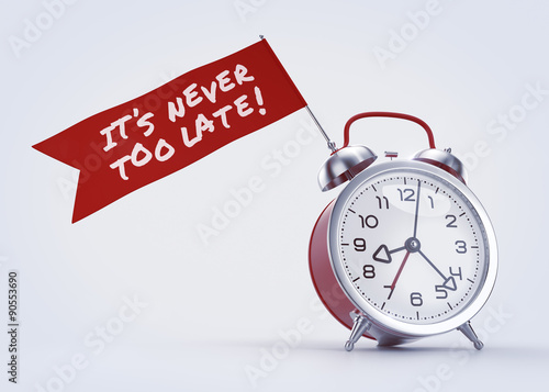 Never Too Late! Alarm clock with a red banner and written phrase on it. 3D rendered graphics on light background. The text on the banner created with the Permanent Marker font under Apache License V2. © Sergey Tarasov