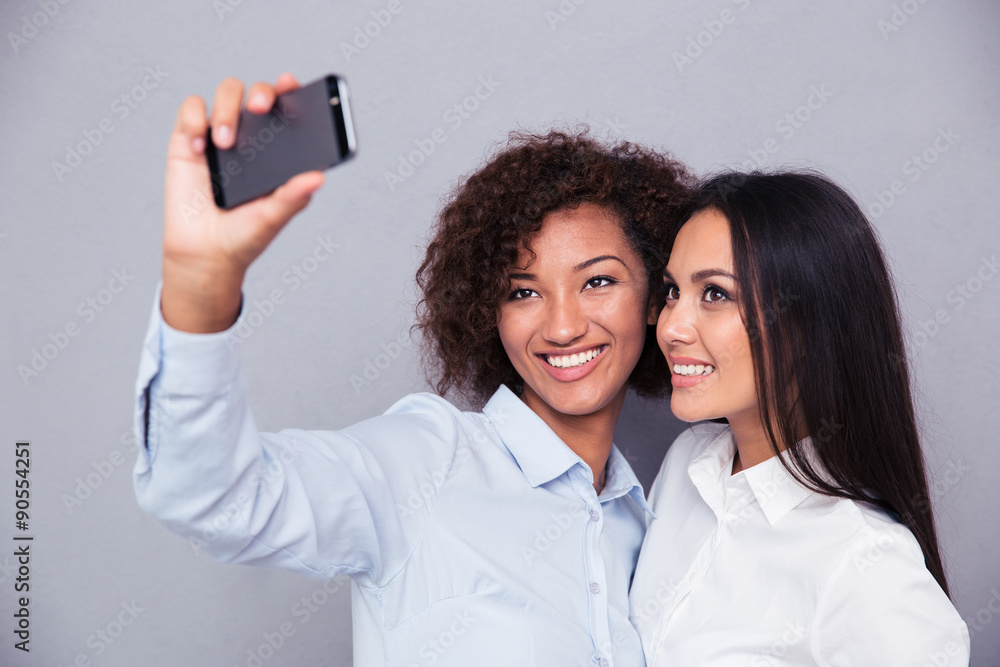 Smiling two girls making selfie photo on smartphone Smiling two girls making selfie photo on smartphone