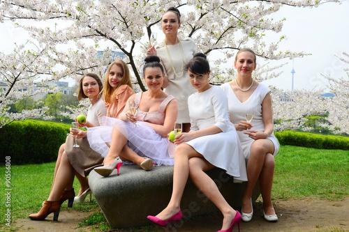 Obraz na płótnie Girls with champagne celebrating in sakura's garden. w salonie
