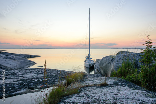 Sailboat moored long side a small rocky island