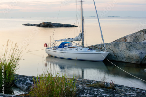 Sailboat moored long side a small rocky island